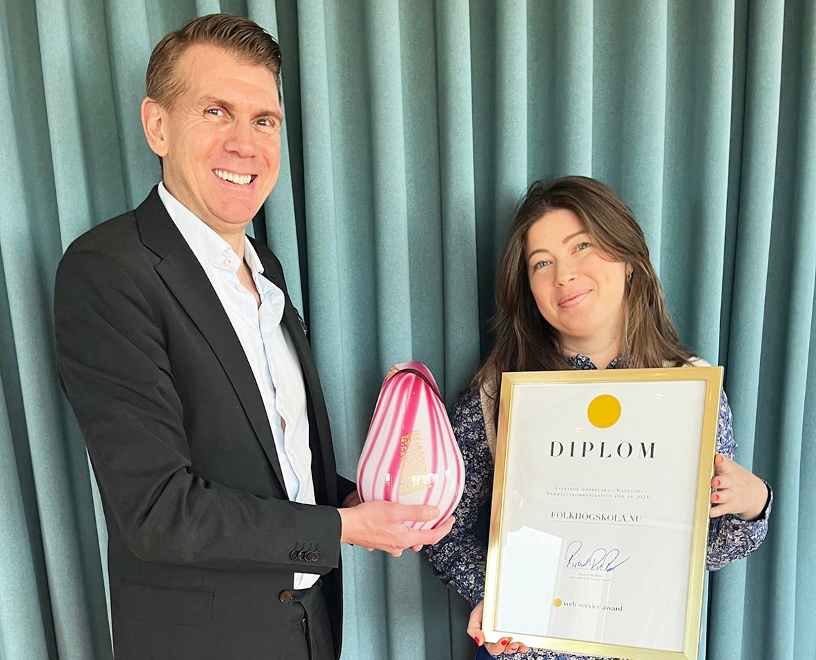 En leende man överlämnar en glasskulptur till en leende kvinna.