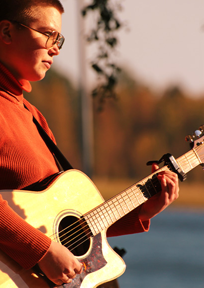 Bild: Deltagare på Singer/Songwriter spelar gitarr utomhus.